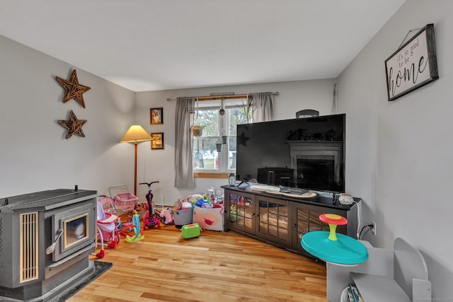 game room featuring a wood stove and hardwood / wood-style flooring