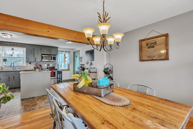 dining room featuring a wealth of natural light, sink, a notable chandelier, and light wood-type flooring