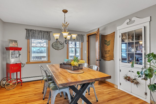 dining room with light hardwood / wood-style flooring, a baseboard heating unit, and an inviting chandelier