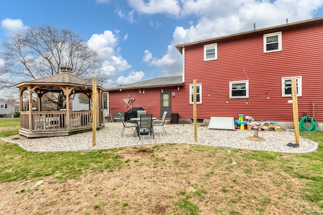 rear view of house with a gazebo, a deck, and a lawn