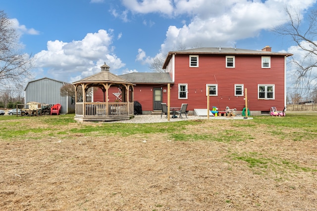 rear view of house featuring a gazebo and a lawn