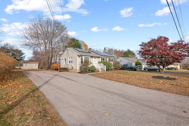 view of front of house with a front yard, solar panels, and a storage shed