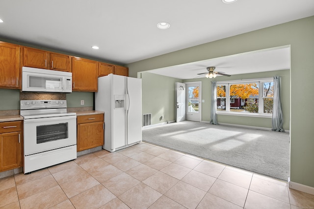 kitchen with white appliances, light colored carpet, and ceiling fan