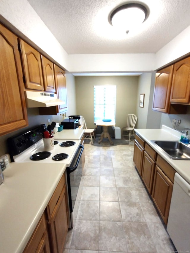 kitchen featuring a textured ceiling, white appliances, light tile patterned floors, and sink