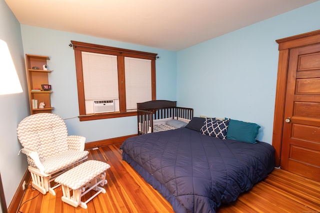 bedroom with cooling unit and wood-type flooring