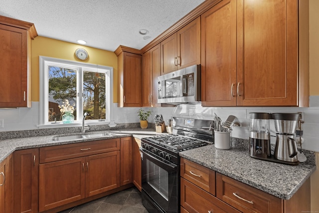 kitchen featuring light stone countertops, black range with gas stovetop, a textured ceiling, and sink