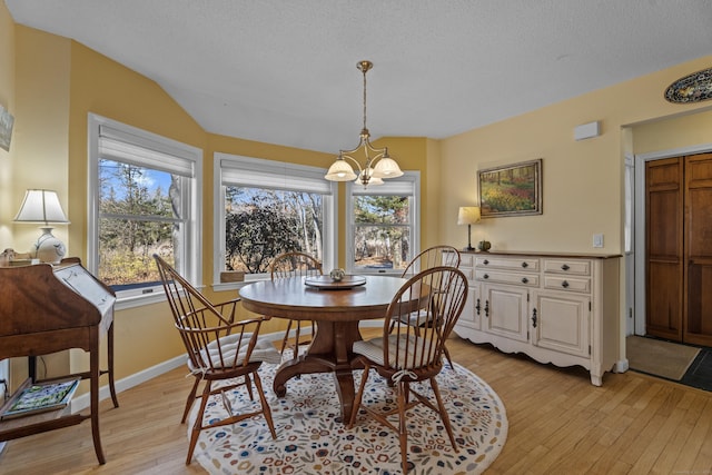 dining area featuring a chandelier, a textured ceiling, light hardwood / wood-style flooring, and lofted ceiling