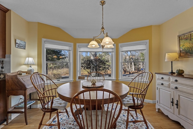 dining room featuring light hardwood / wood-style floors, an inviting chandelier, and vaulted ceiling