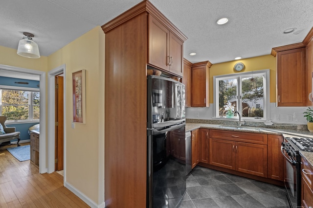 kitchen featuring light stone counters, dark hardwood / wood-style flooring, black appliances, and plenty of natural light