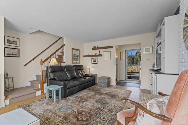 living area with stairway, baseboards, a textured ceiling, and wood finished floors