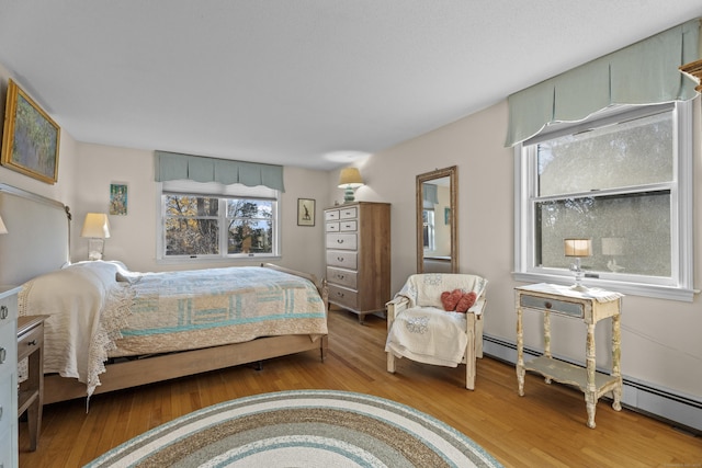 bedroom featuring hardwood / wood-style floors and a baseboard heating unit