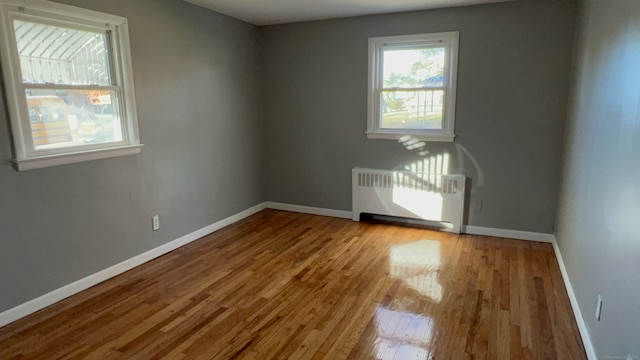 unfurnished room featuring radiator and light wood-type flooring