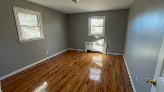 unfurnished room featuring radiator heating unit and light hardwood / wood-style floors