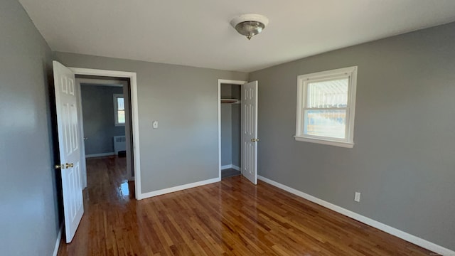 unfurnished bedroom featuring hardwood / wood-style floors, radiator heating unit, and a closet