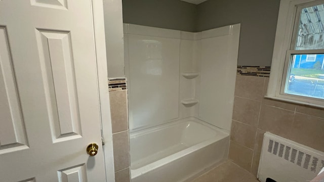 bathroom featuring radiator heating unit, bathing tub / shower combination, and tile walls