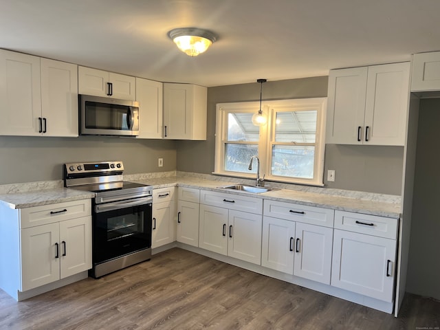 kitchen with light stone countertops, white cabinetry, sink, stainless steel appliances, and dark hardwood / wood-style floors