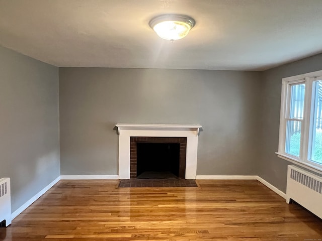 unfurnished living room with a fireplace, hardwood / wood-style flooring, and radiator