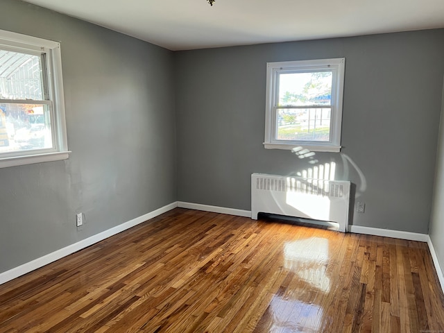 unfurnished room featuring hardwood / wood-style flooring and radiator heating unit