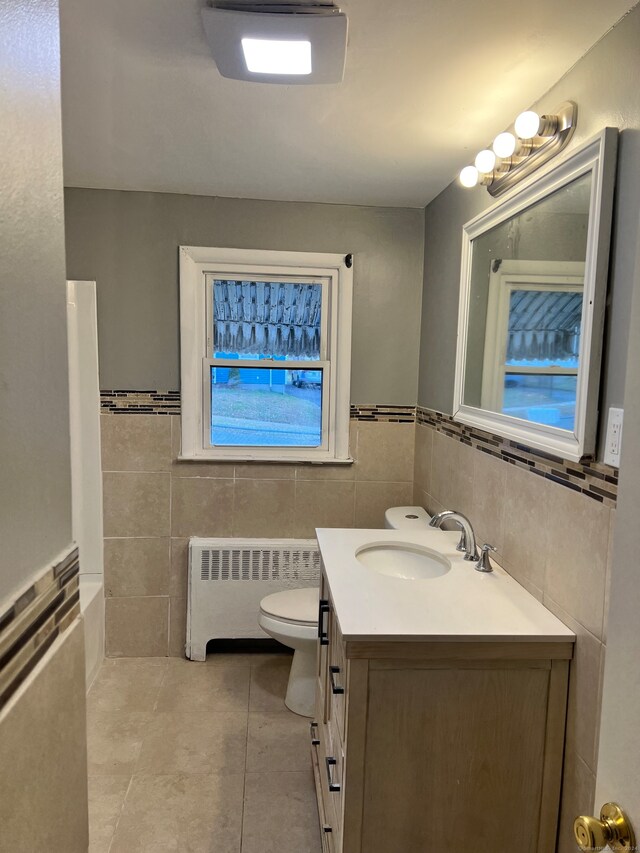 bathroom with radiator heating unit, vanity, tile walls, and tile patterned flooring