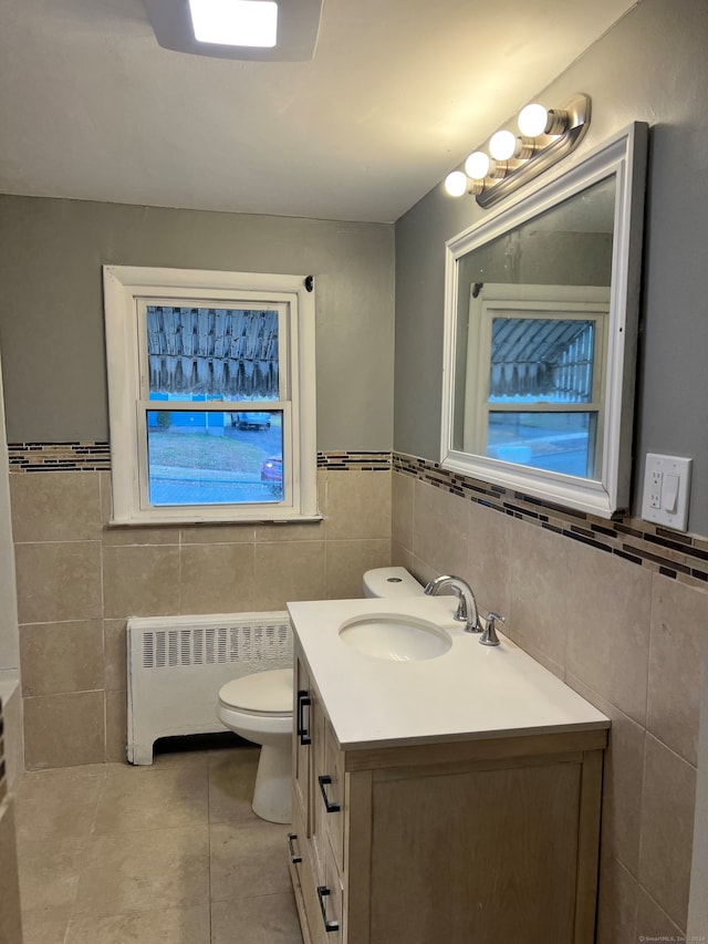 bathroom featuring radiator heating unit, vanity, toilet, and tile walls