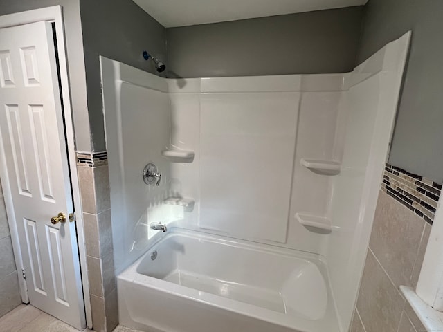 bathroom with washtub / shower combination, tile patterned flooring, and tile walls