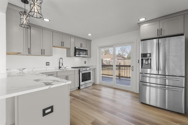 kitchen with light stone countertops, light hardwood / wood-style floors, stainless steel appliances, sink, and gray cabinets