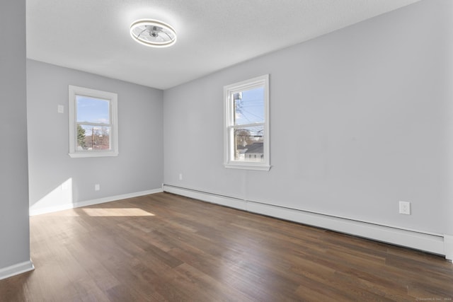 spare room with baseboard heating, a wealth of natural light, dark hardwood / wood-style flooring, and a textured ceiling