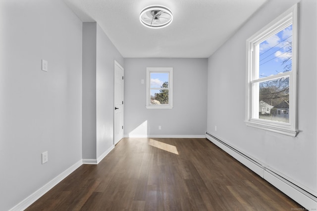 spare room with dark hardwood / wood-style floors and a baseboard heating unit