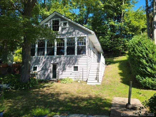 view of side of property with a sunroom and a yard