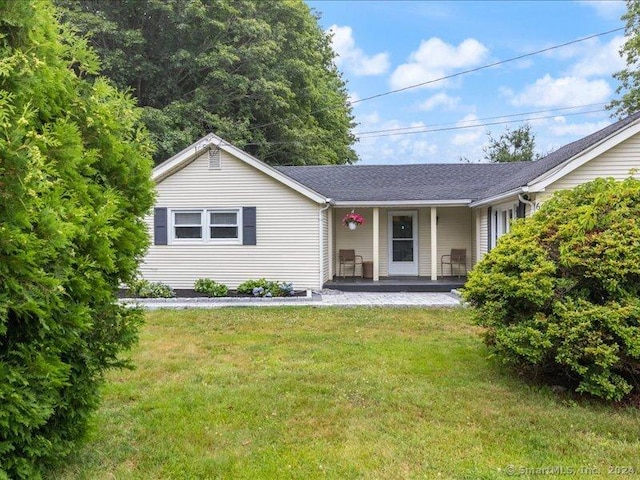 ranch-style house featuring covered porch and a front yard