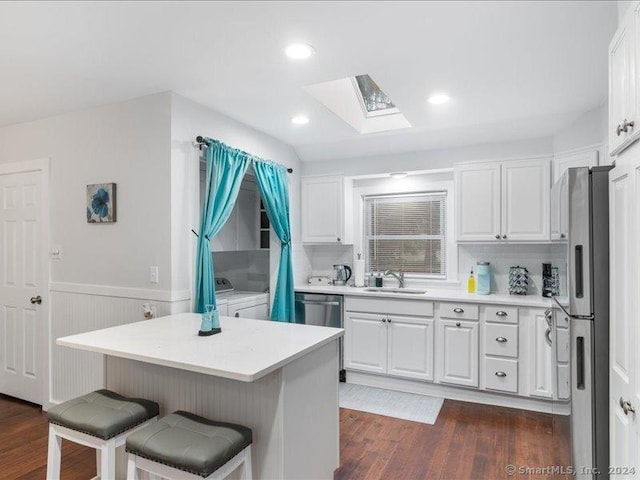 kitchen featuring white cabinets, washer and dryer, dark hardwood / wood-style flooring, and sink