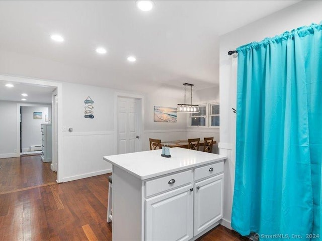 kitchen featuring kitchen peninsula, white cabinetry, hanging light fixtures, and dark wood-type flooring