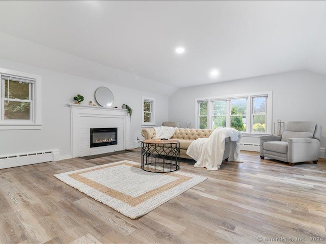 bedroom with light hardwood / wood-style floors, a baseboard radiator, and vaulted ceiling