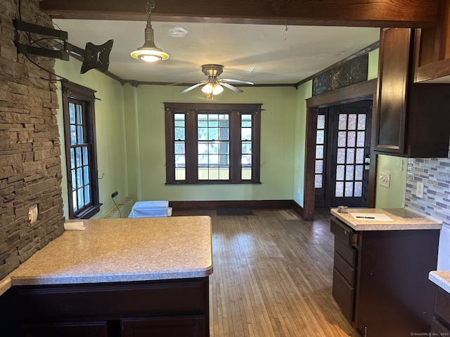 kitchen featuring backsplash, ornamental molding, ceiling fan, wood-type flooring, and hanging light fixtures