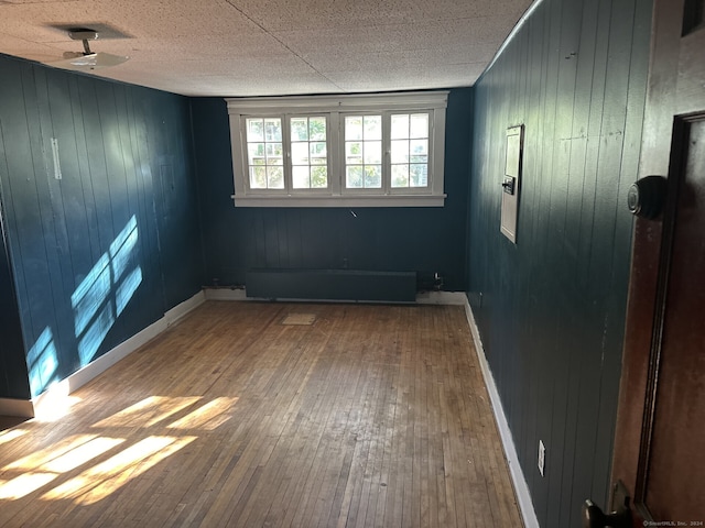 unfurnished room featuring hardwood / wood-style floors, ceiling fan, and wooden walls