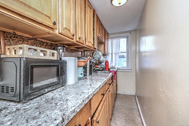 kitchen with light stone countertops, sink, and light tile patterned flooring