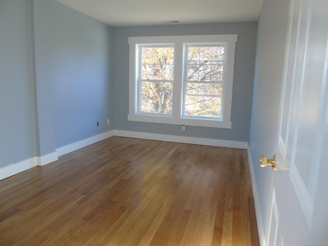 empty room with baseboards, visible vents, and wood finished floors