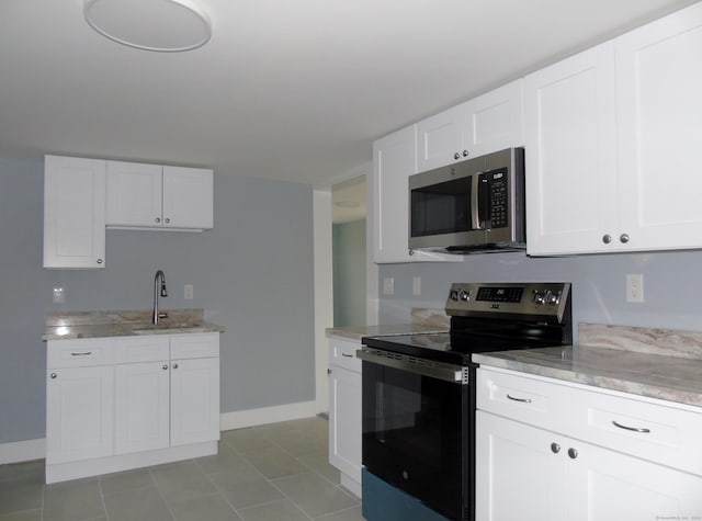 kitchen featuring white cabinets, a sink, stainless steel appliances, and light stone counters