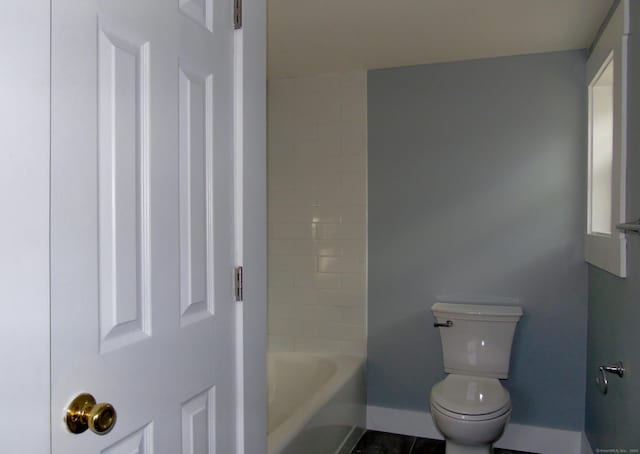 bathroom with toilet, tile patterned floors, and a tub to relax in