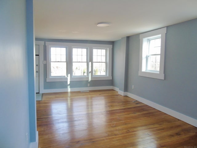 empty room featuring baseboards, visible vents, and wood finished floors