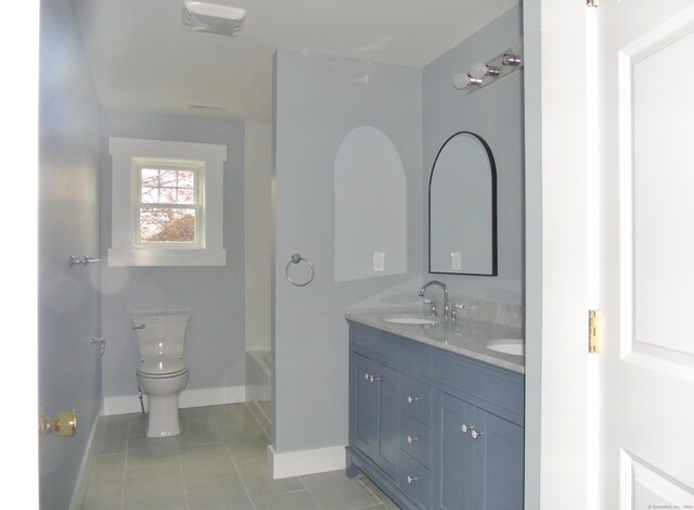 bathroom featuring baseboards, double vanity, toilet, a sink, and tile patterned flooring
