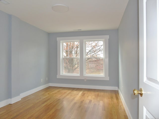 spare room featuring baseboards, visible vents, and light wood-type flooring