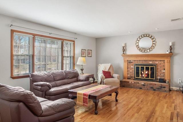 living room featuring a brick fireplace and light hardwood / wood-style flooring