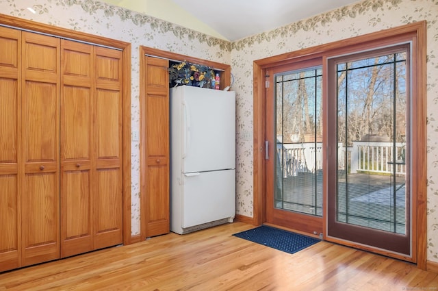 doorway to outside with light wood-type flooring and vaulted ceiling