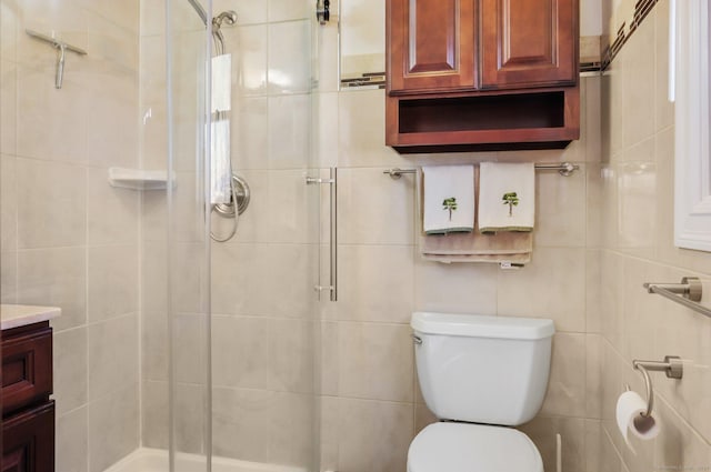 bathroom with vanity, toilet, a shower with door, and tile walls