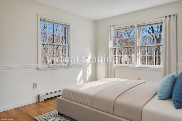 bedroom featuring hardwood / wood-style floors, baseboard heating, and multiple windows