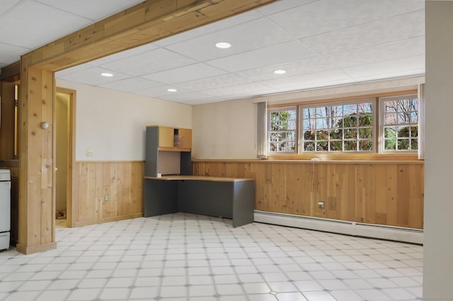 kitchen featuring wood walls, a drop ceiling, a baseboard radiator, and white stove