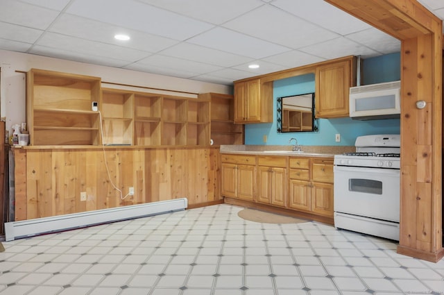 kitchen with a drop ceiling, white appliances, a baseboard heating unit, sink, and wooden walls