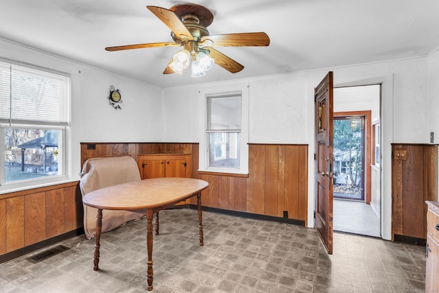 sitting room featuring ceiling fan and wooden walls