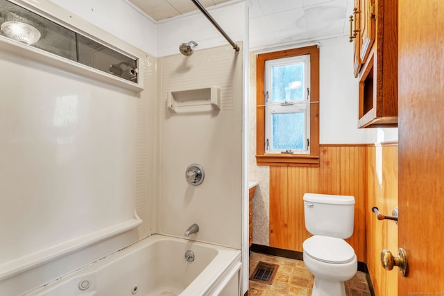 bathroom featuring shower / tub combination, wood walls, and toilet